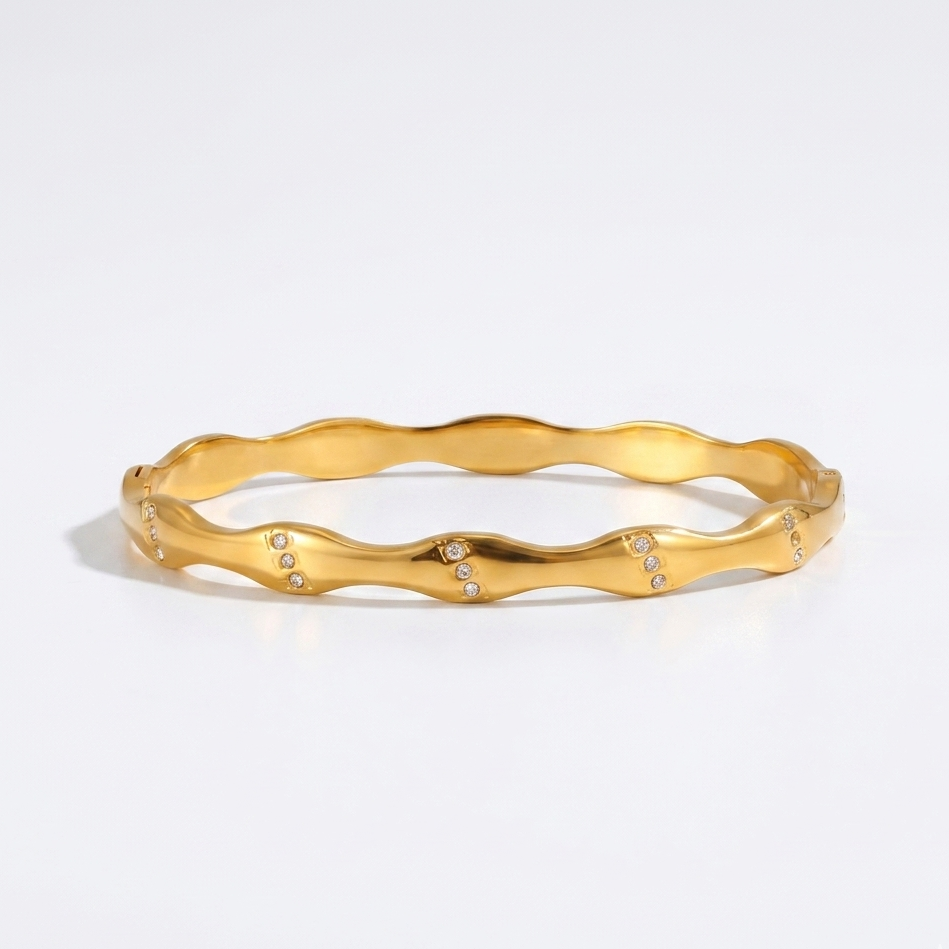 Gold bracelet with a wavy design on a light gray background